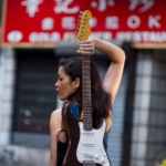 Ebony Tay holds a custom “oxtail” stratocaster, formerly owned by a member of the Wailers. Ebony Tay, a guitarist and composer poses for the Six String Vault.